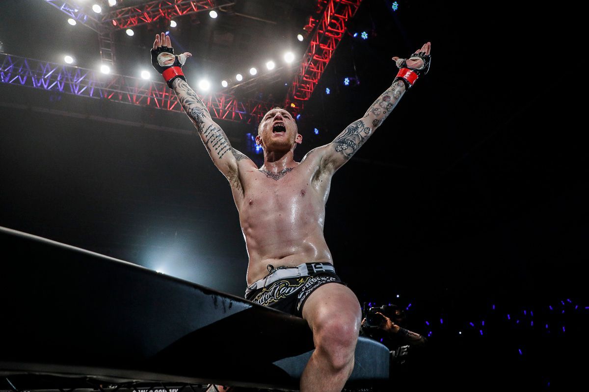 Australian Muay Thai fighter Elliot Compton celebrates his victory by climbing the cage