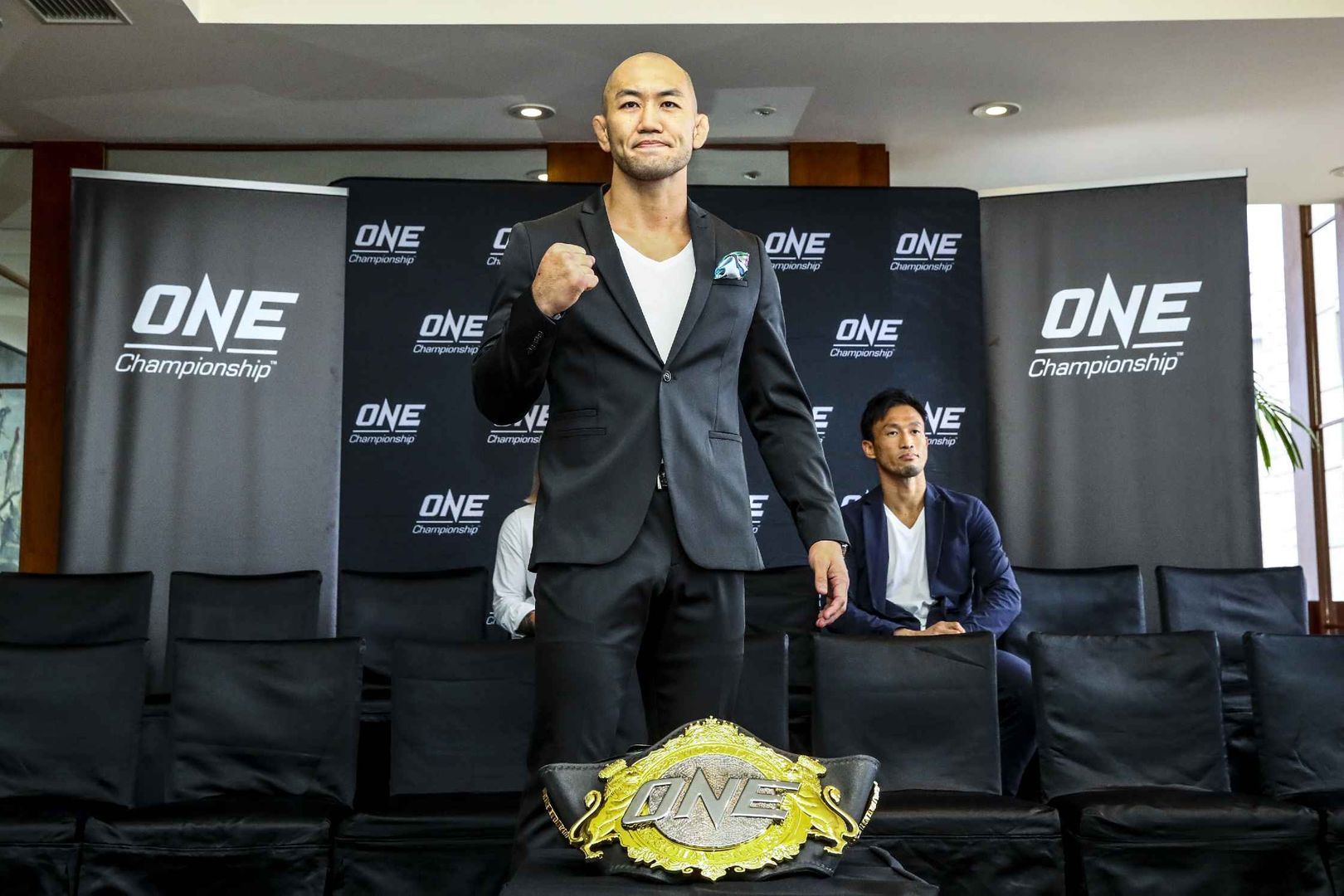 Yushin Okami stands behind the ONE Championship belt