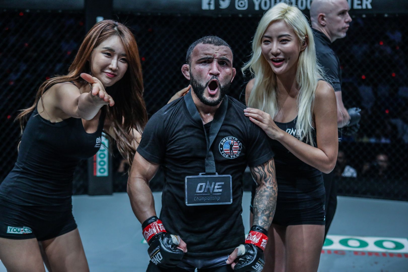 Brazilian mixed martial artist John Lineker celebrates his debut win in ONE with the winner's medal and the ring girls