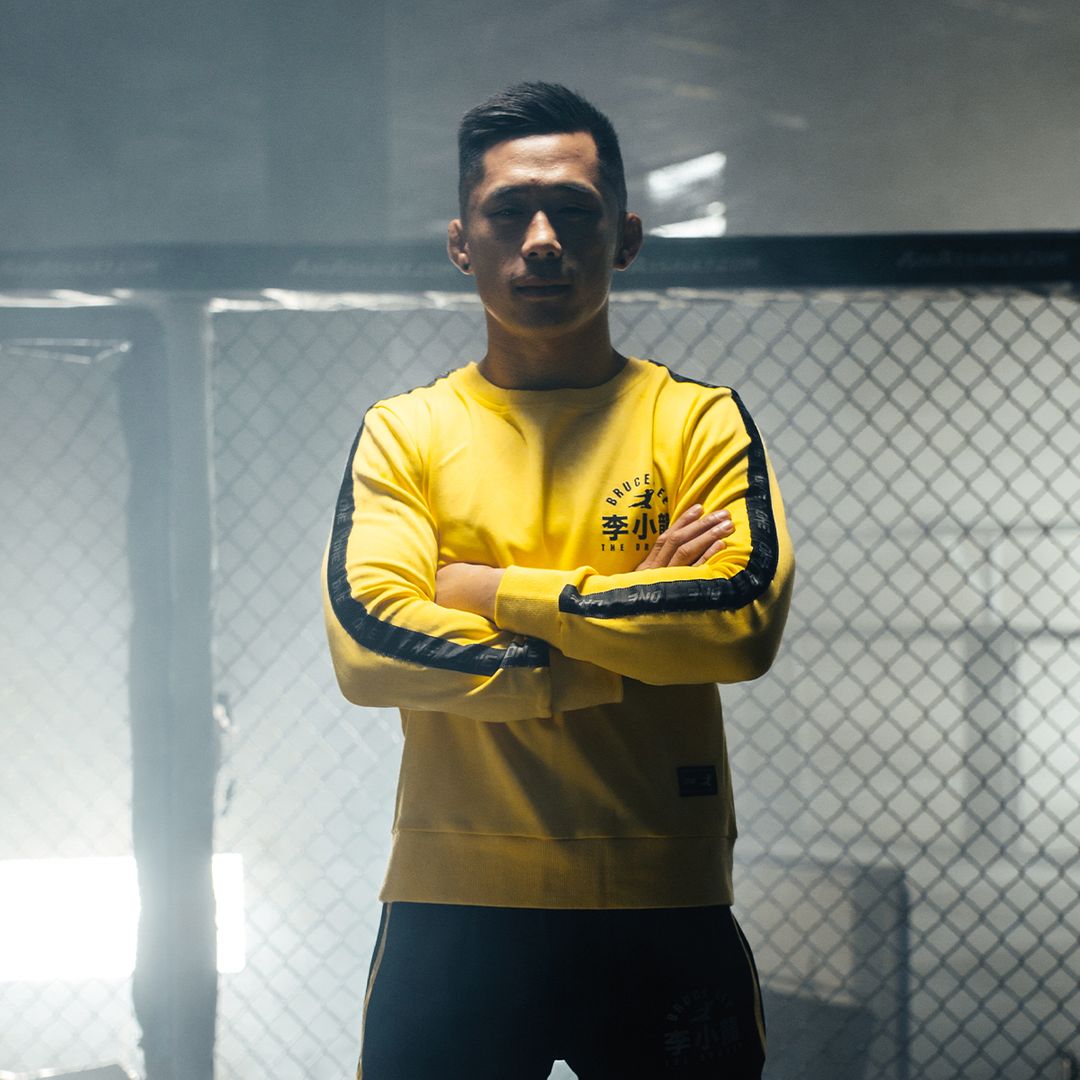 Martin Nguyen poses in the Game Of Death Pullover from the ONE X Bruce Lee Collection from ONE.SHOP!